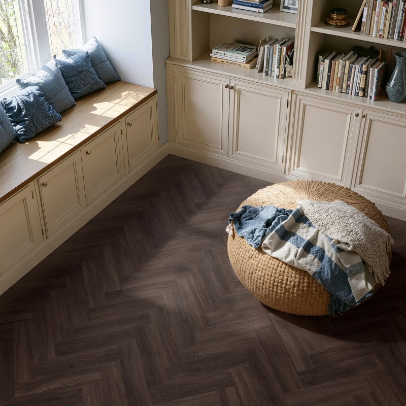 Dark umber effect herringbone LVT flooring laid in a bedroom